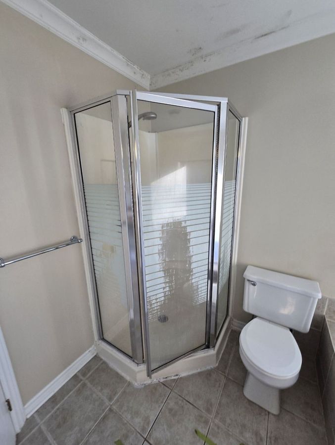 Ancienne douche d'angle à porte vitrée.