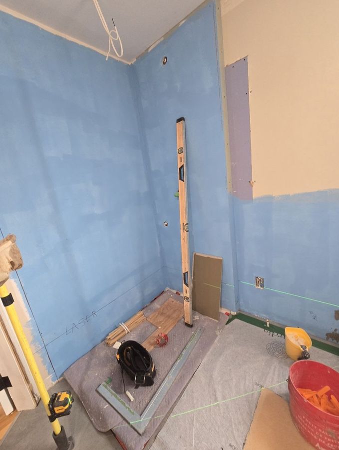 Membrane d'étanchéité bleue sur les murs de la douche et du bain, alignement au laser.