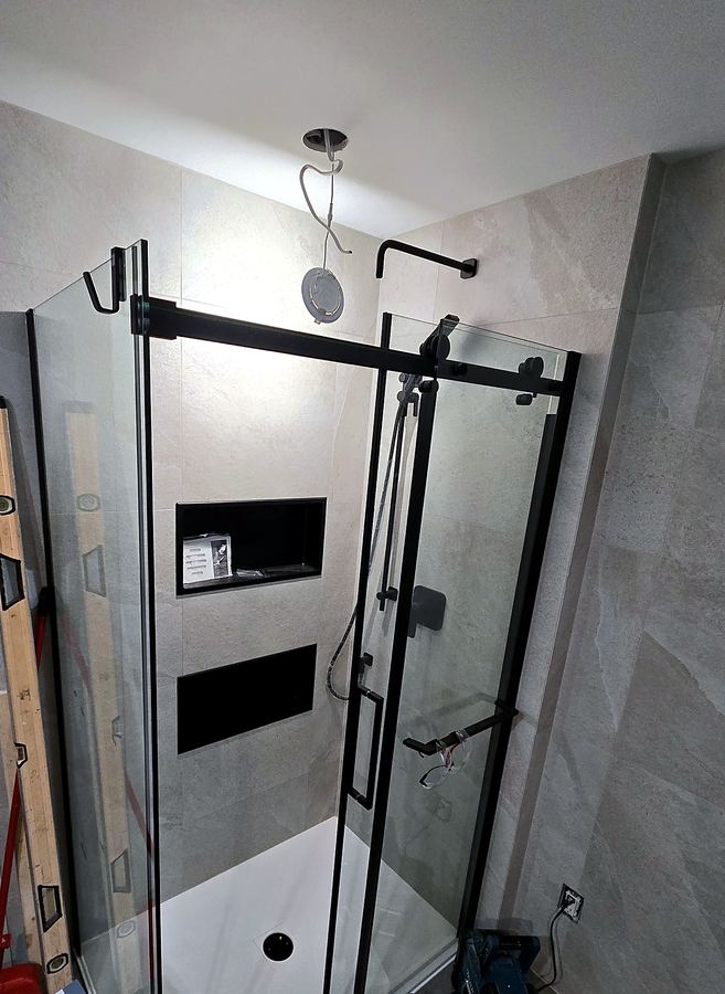 Douche à cadre noir et niches encastrées en installation.