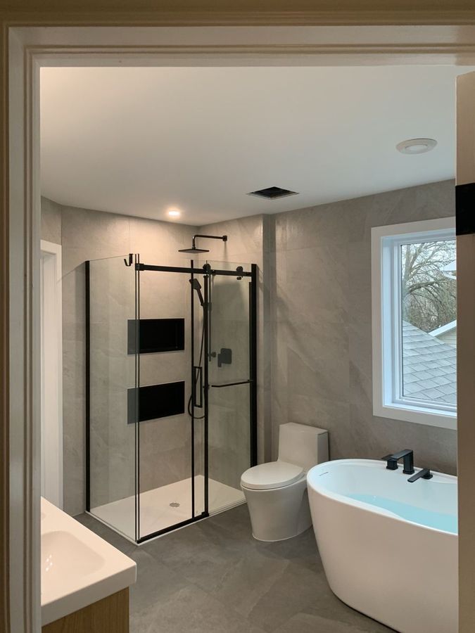 Vue d'ensemble : douche vitrée, toilette et bain autoportant.