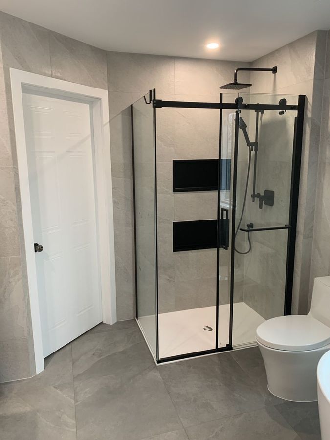 Douche à cadre noir, niches encastrées et pomme de douche pluie.