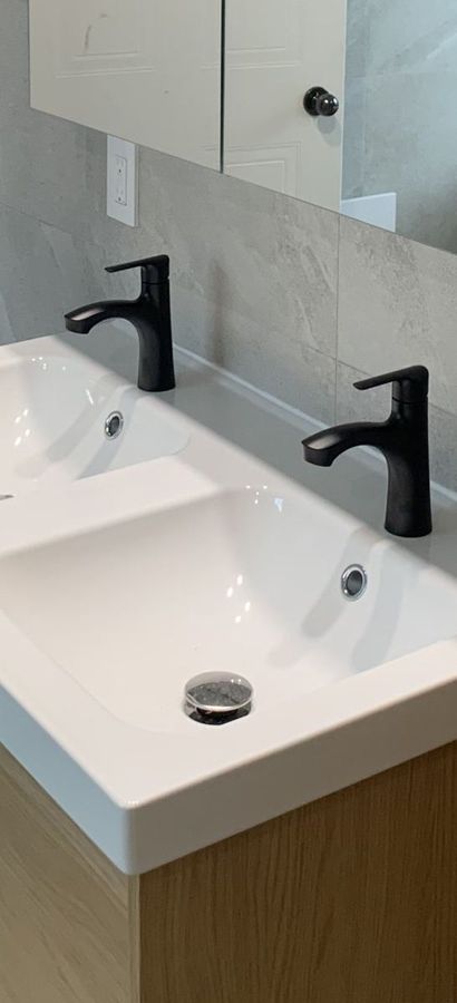 Lavabo double et robinets noirs mats.